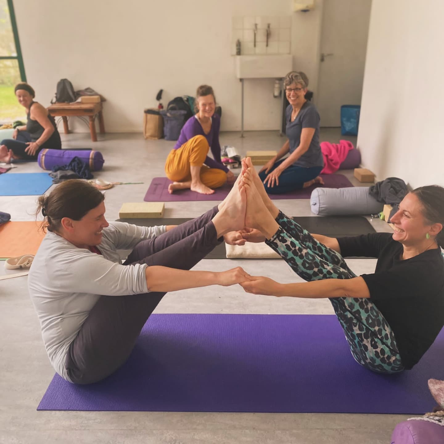 Yoga students in partner practice, laughing together