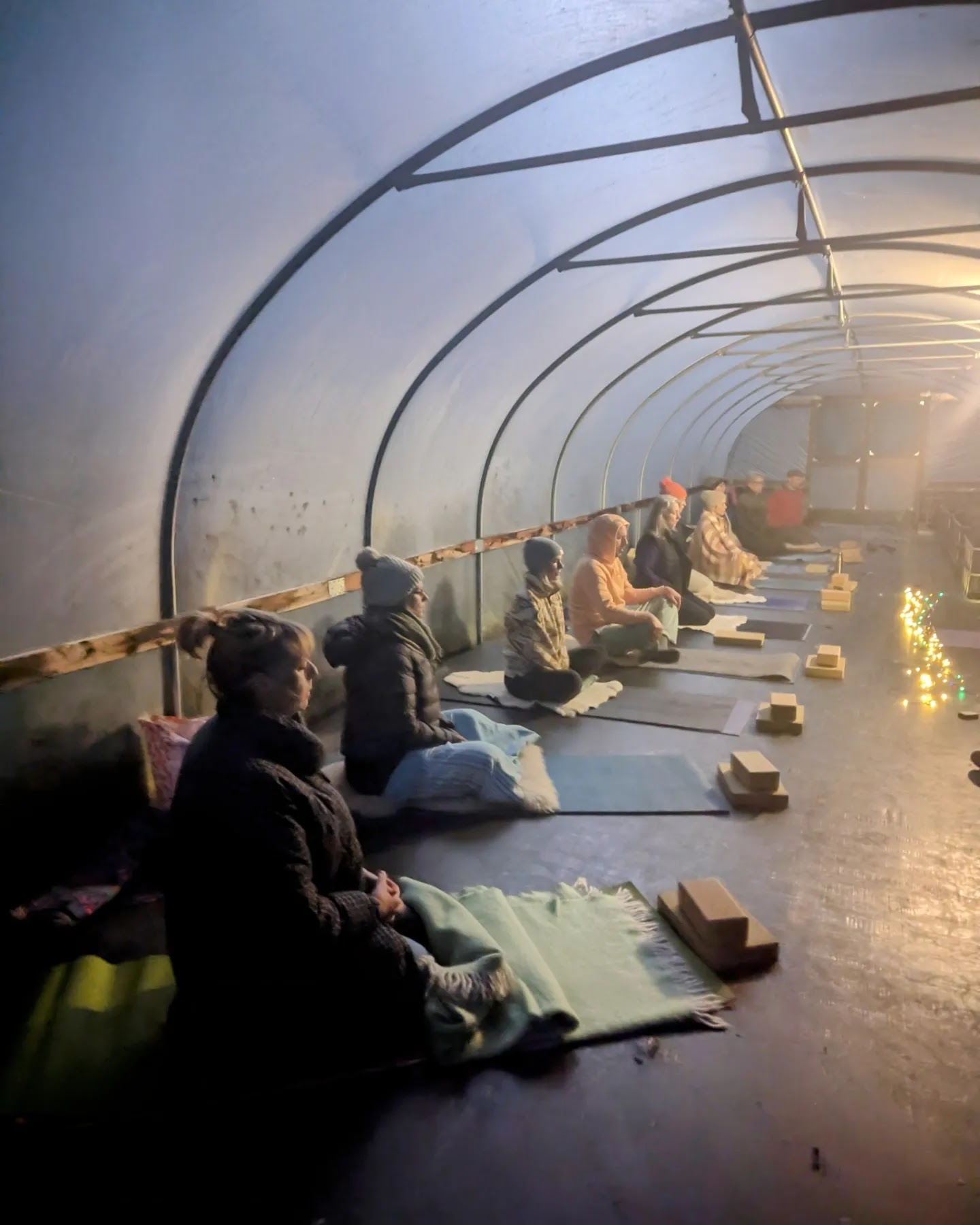 Winter yoga gathering in the polytunnel by candlelight